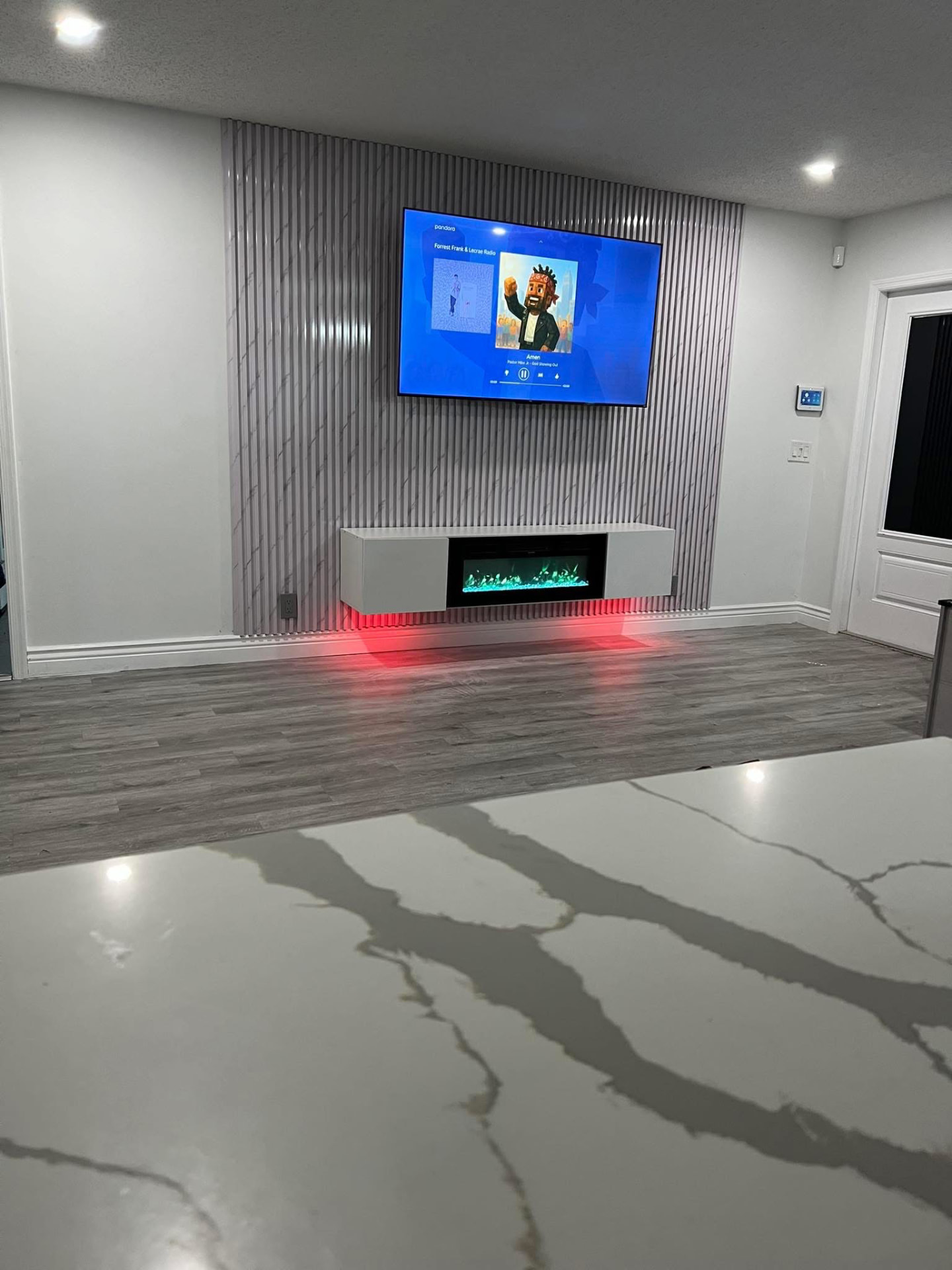 Light fluted accent wall with mounted TV and floating fireplace console